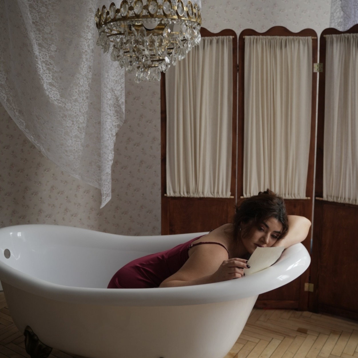Leeza Maroe reading a letter in a clawfoot bathtub