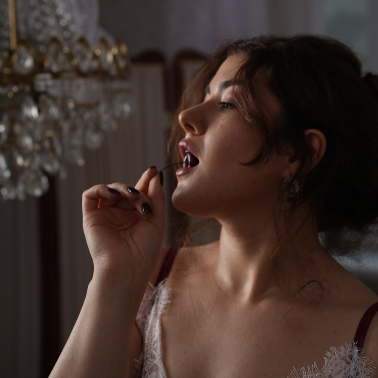 Leeza Maroe eating a cherry beneath a chandelier